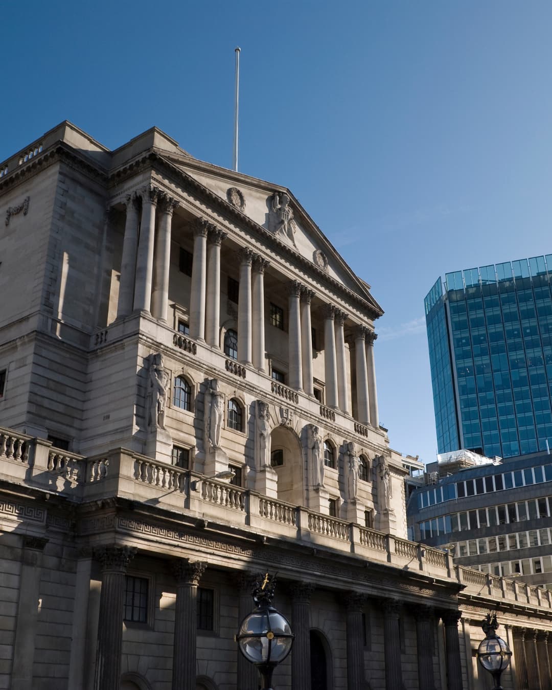 A classical stone building in the City of London beside a modern glass office tower