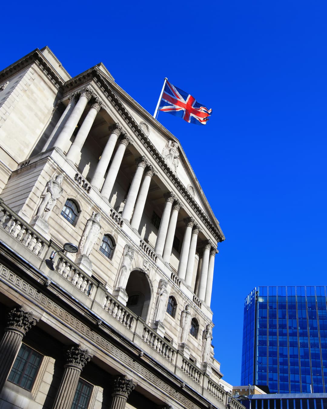A classical stone building in the City of London with a Union flag flying above it