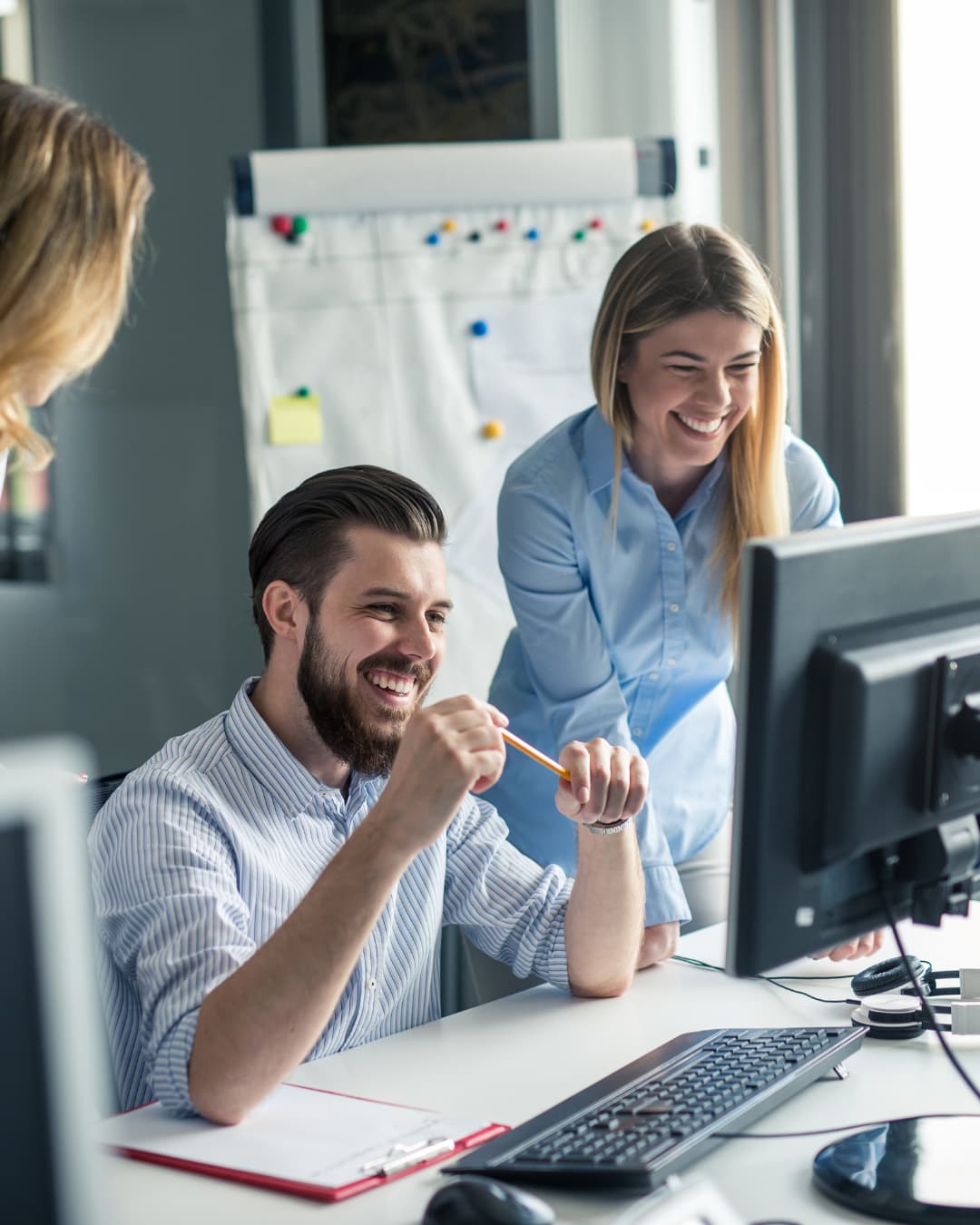 Two colleagues reviewing figures together on a desktop monitor