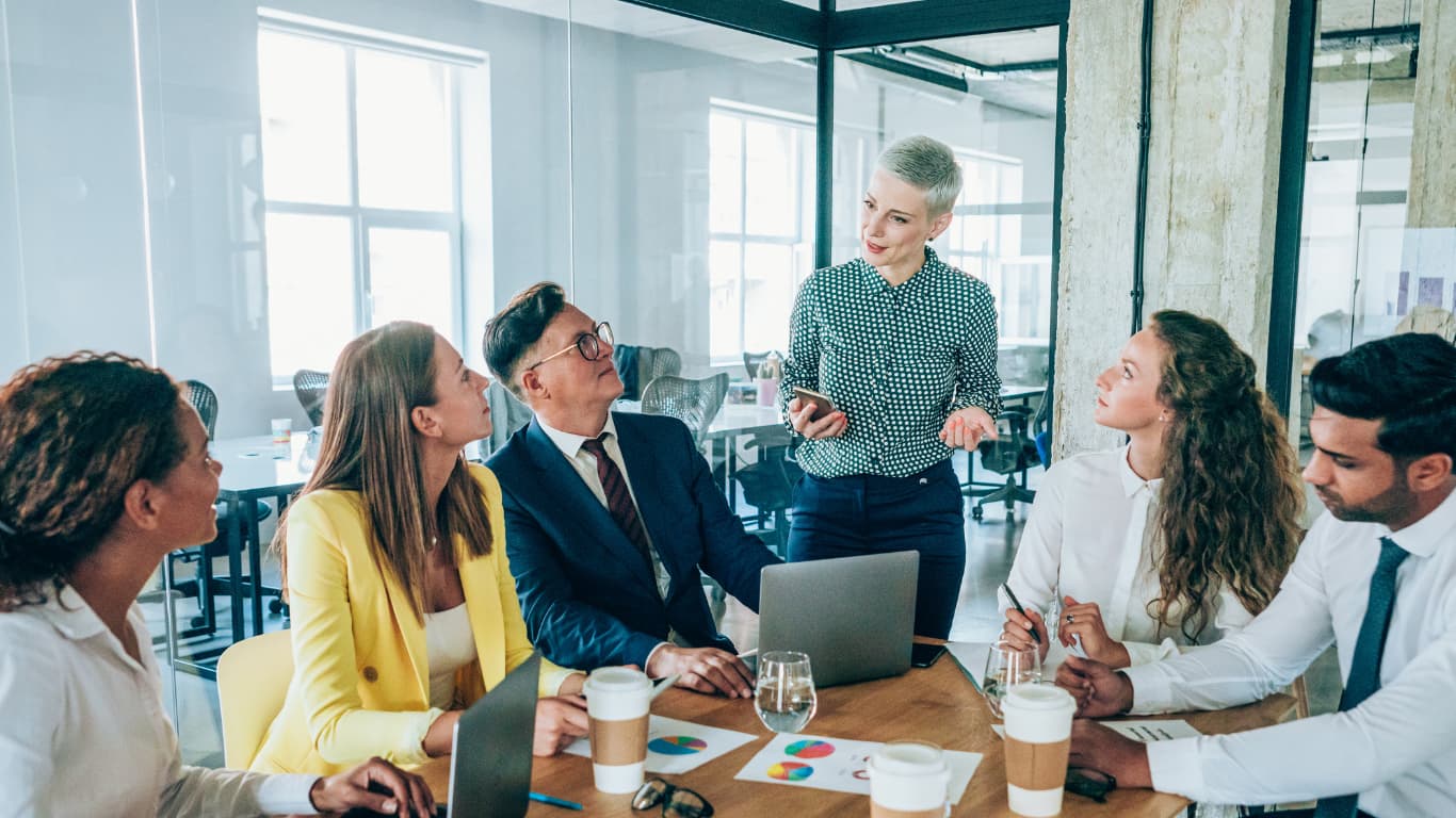 Colleagues meeting around a boardroom table in a bright office