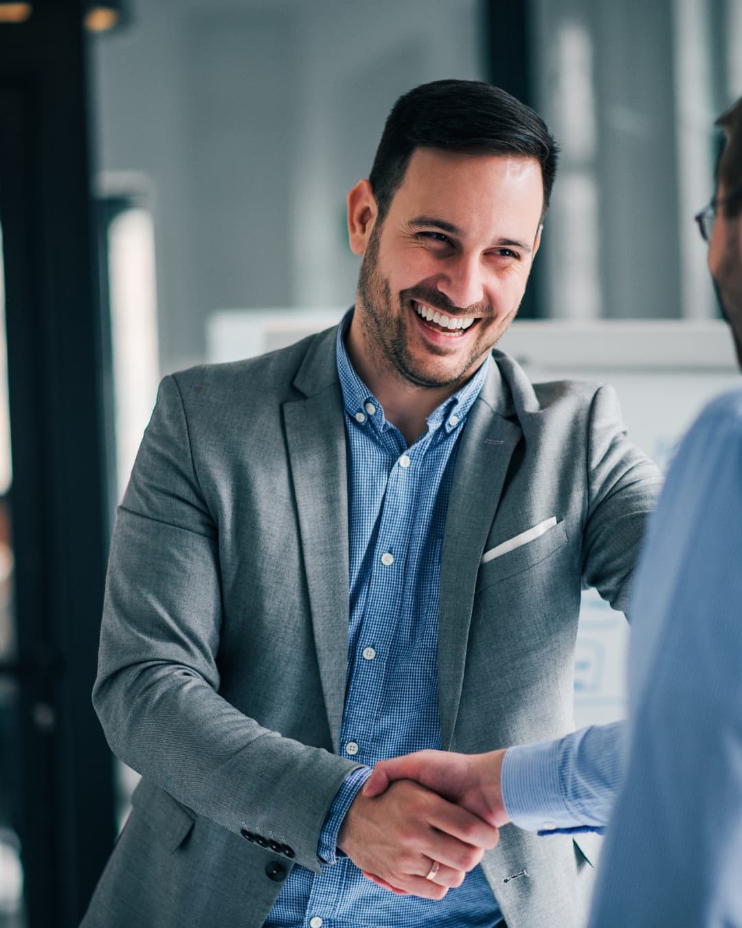 A man in a blazer smiling during a conversation in an office